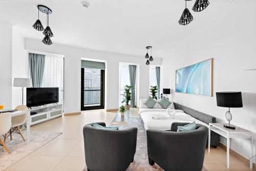 a living room with a couch and chairs and a tv at Skyline Views 2BR Near Burj Khalifa & Dubai Mall with Pool Access in Dubai