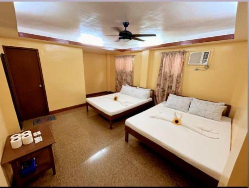 a room with two beds and a ceiling fan at mam olson pensionne house in El Nido
