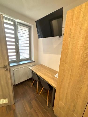 a dining room with a wooden table and a flat screen tv at Apartament Residence Nysa in Nysa