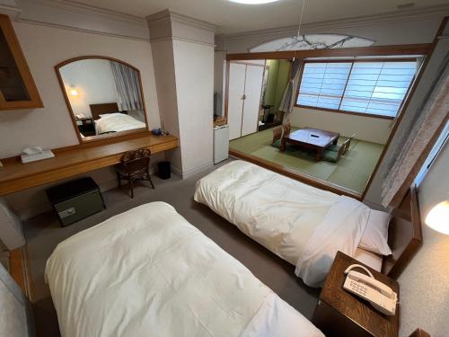 ein Hotelzimmer mit zwei Betten und einem Spiegel in der Unterkunft Hotel Marsh Land in Kushiro