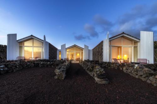 a building with large windows and a stone wall at Sea Vine - Azores Eco Lodging in Cais do Galego