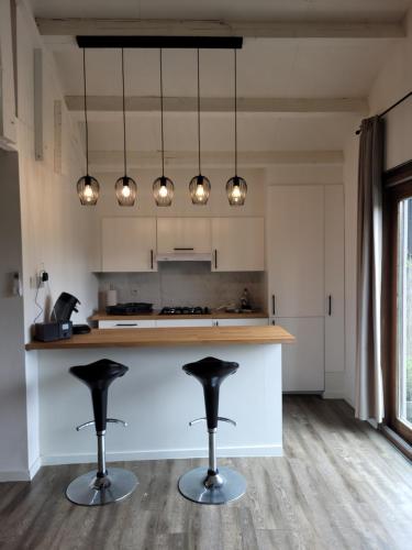 a kitchen with two bar stools in front of a counter at Rustig gelegen chalet Kapeki met tuin aan het water in Geel