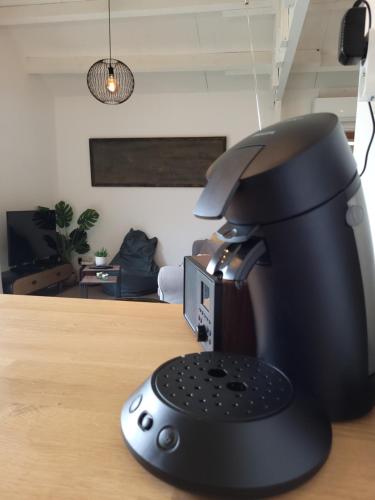 a black coffee machine sitting on a wooden table at Rustig gelegen chalet Kapeki met tuin aan het water in Geel