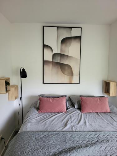 a bedroom with a bed with two pink pillows at Rustig gelegen chalet Kapeki met tuin aan het water in Geel