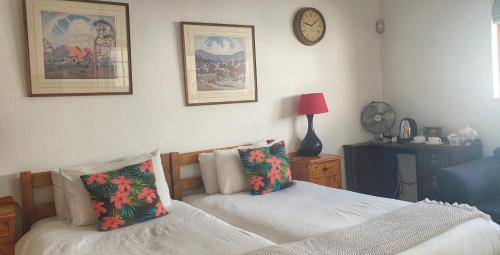a bedroom with two beds and a clock on the wall at Camdeboo Cottages in Graaff-Reinet