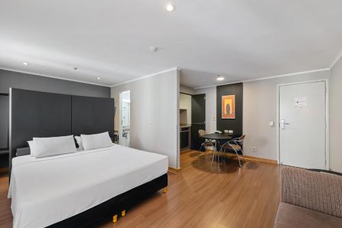 a bedroom with a large white bed and a table at Slaviero São Paulo Ibirapuera in Sao Paulo