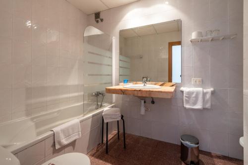 a bathroom with a sink and a tub and a mirror at Eco Avenida Hotel & Parking in Benicàssim