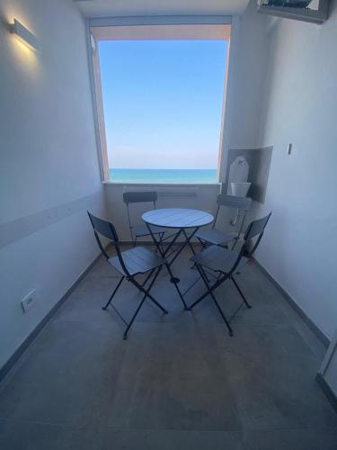 a table and chairs in a room with a large window at NON DISTA APARTMENT Appartamentino sul mare in Ortona