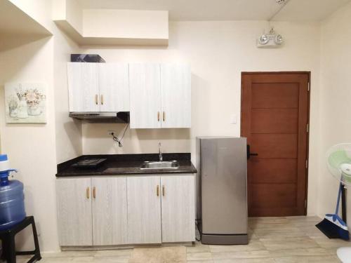 バギオにあるRelaxing 1-BR at City Center Goshen Land Towersの白いキャビネットとステンレス製の冷蔵庫を備えたキッチン