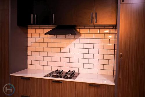 a kitchen with a stove and a white tiled wall at Private Villa in Kollam with Pool in Kollam