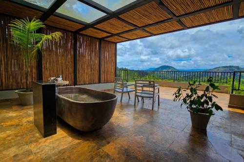 a large bathroom with a tub and a table and chairs at Maram Resort Mamalakandam in Mamalakandam