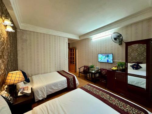 a hotel room with two beds and a television at Hà Giang Hotel Sapa in Sa Pa