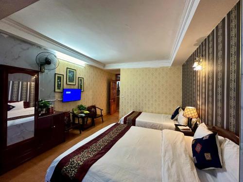 a hotel room with two beds and a television at Hà Giang Hotel Sapa in Sa Pa