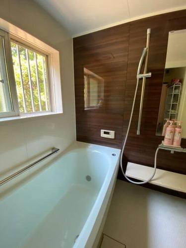 a bathroom with a bath tub and a window at Grace House グレイスハウス- Country Home Relaxation in Okawa