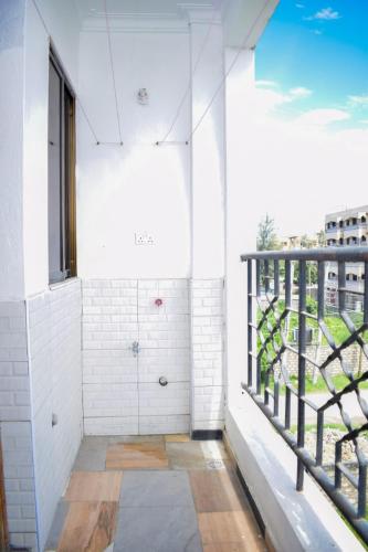 a room with a balcony with a shower and a window at Lux Suites Casey's Apartments Bamburi in Bamburi