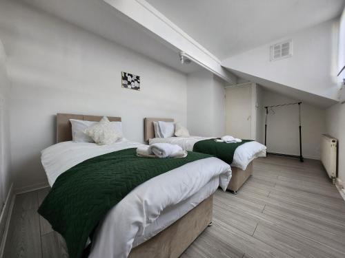 zwei Betten mit grüner und weißer Bettwäsche in einem Zimmer in der Unterkunft The Greenhouse near Leeds City Centre in Killingbeck