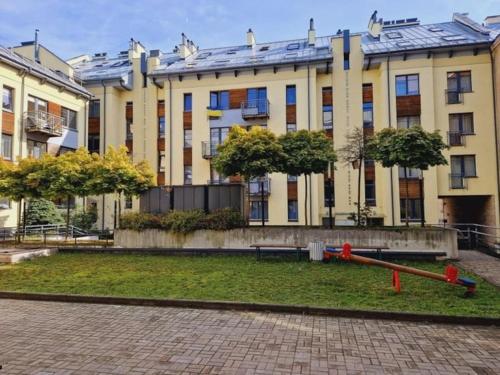 a large yellow building with trees in front of it at Sv1 Amber Oldtown SELF CHECK-IN by QuarterStays in Vilnius