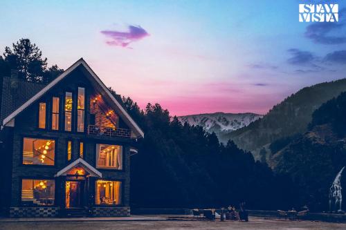 a house with a sunset in the mountains at StayVista at Frozen Fall - Tangmarg with Breakfast Included in Gulmarg