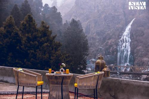 two chairs and a table with a view of a waterfall at StayVista at Frozen Fall - Tangmarg with Breakfast Included in Gulmarg
