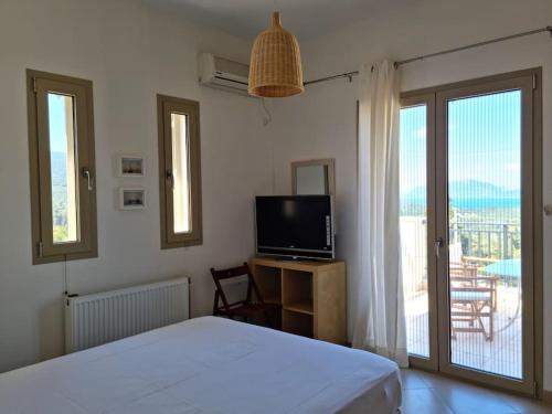 a bedroom with a bed and a television and a balcony at Stunning View Villa in Sami in Chaliotata