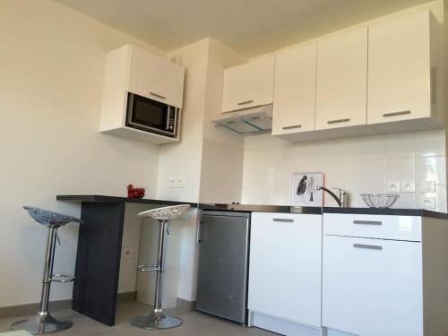 une cuisine avec des armoires blanches et un comptoir avec des tabourets dans l'établissement Ma place au sud Nice 405, à Nice