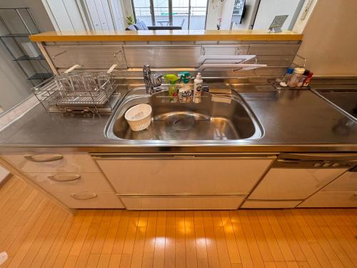 a stainless steel kitchen sink with a dish rack at Comfy House Namba in Osaka