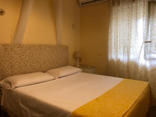a bedroom with a white bed with a window at B&B Xenia in Mongiove