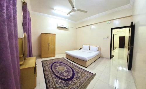 a bedroom with a bed and a rug in it at Al Afiah Corniche Hotel Apartment in Sur
