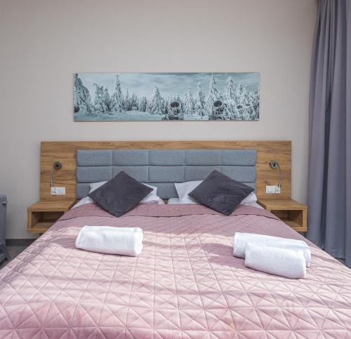 a large bed with a pink blanket and two pillows at Aparthotel Apartamenty Czarna Góra 233 in Sienna