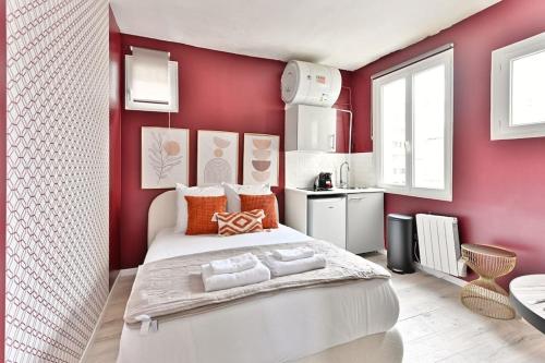 une chambre avec un grand lit blanc dans un mur rouge dans l'établissement Studio Cosy près de Montparnasse - II, à Paris