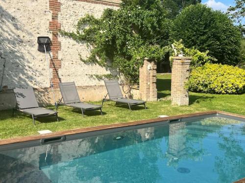 une piscine dans la cour d'une maison avec deux chaises dans l'établissement Les Roseaux, 1h de Paris, Grand Jardin, Piscine, à Venables