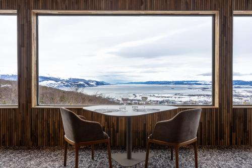 a dining room with a table and chairs and large windows at Los Acebos Ushuaia Hotel in Ushuaia