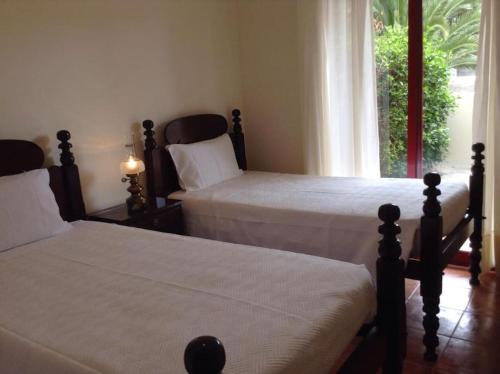 ein Schlafzimmer mit zwei Betten und einem Fenster in der Unterkunft Casa da Palmeira Porto Santo in Vila Baleira