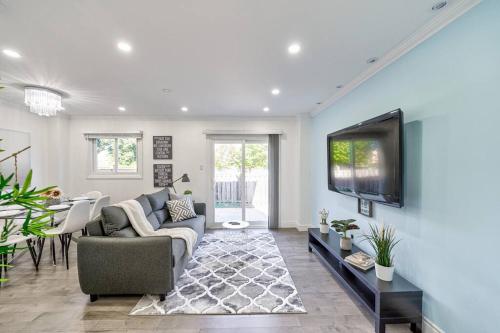 a living room with a couch and a tv on a wall at 4BR Scarborough Gem, Freshly Renovated, 7 Car Parking in Toronto