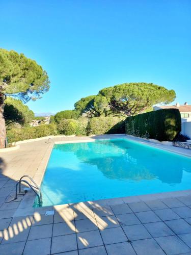 une piscine avec des arbres en arrière-plan dans l'établissement Family house - quiet - common pool - Fréjus, à Fréjus