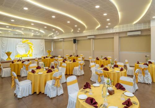 a banquet hall with tables and chairs with yellow table cloths at Oshin Wayanad in Wayanad