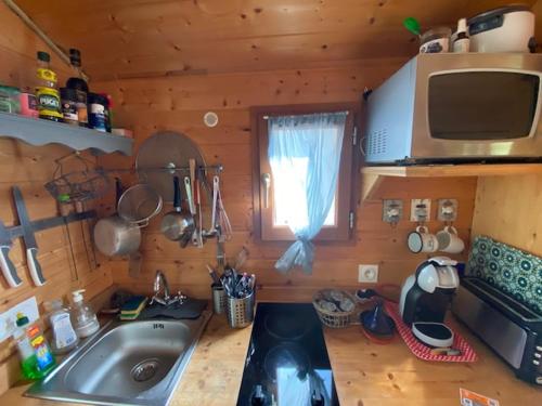 - une cuisine avec évier et une fenêtre dans une cabine dans l'établissement Roulotte 300 m de la Plage tout confort, à Soulac-sur-Mer