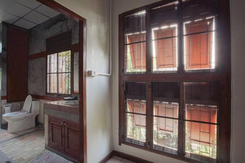 a bathroom with a toilet and a glass door at The Author - Fong Lee CC Lampang Walking Street in Lampang