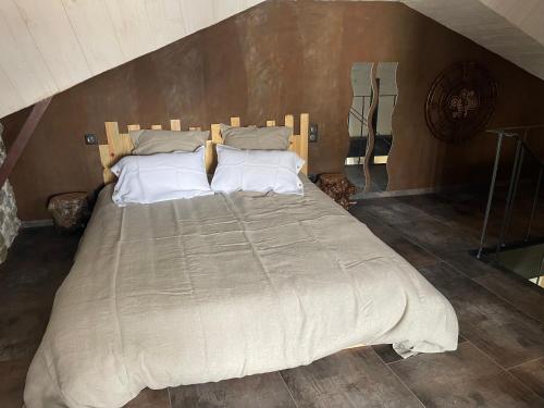 une chambre avec un grand lit avec des oreillers blancs dans l'établissement Le Cabistou, à Saint-Saturnin
