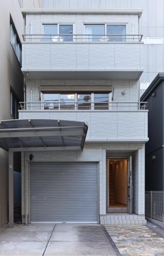 a white house with a garage door and a building at Comfy House Namba in Osaka