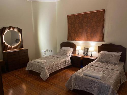 a hotel room with two beds and a mirror at شقه عائلية مؤثثه حي المحمديه جده in Abḩur al Janūbīyah