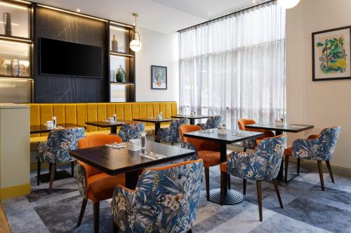 a restaurant with tables and chairs and a flat screen tv at DoubleTree by Hilton London Chelsea in London