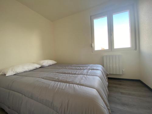 a white bedroom with a bed with a window at Alsace séjours in Pulversheim