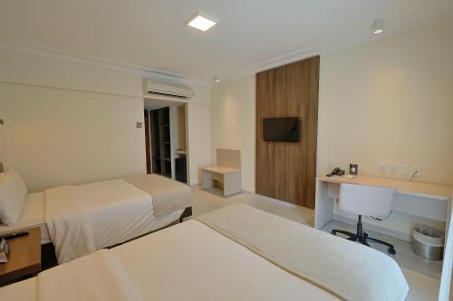 a hotel room with two beds and a television at Del Mar Hotel in Aracaju