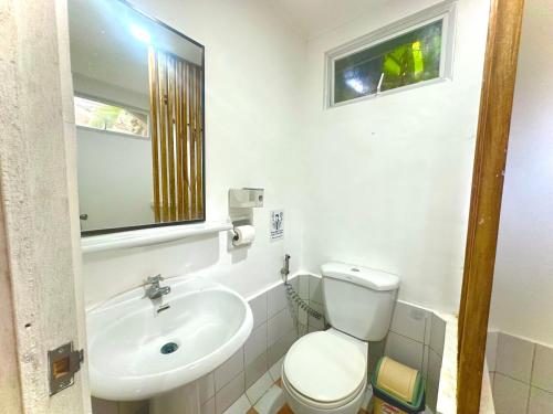 a bathroom with a sink and a toilet and a mirror at RRJ Bungalow 2 1BR,2AC 4 mins walk to the beach in General Luna
