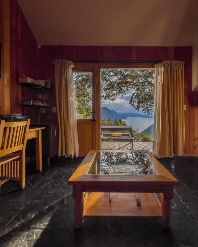 a living room with a table and a large window at Arrayan Lake View Mountain Lodge & Casa De Te Arrayan in San Martín de los Andes