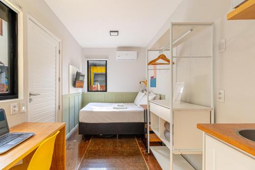 a small room with a bed and a laptop on a desk at Casa Container-Piscina-AC-30min até Aeroporto in Florianópolis