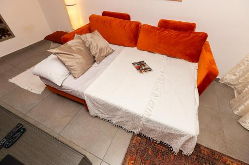 a couch with orange and white sheets and pillows at Pinewood in St Julian's