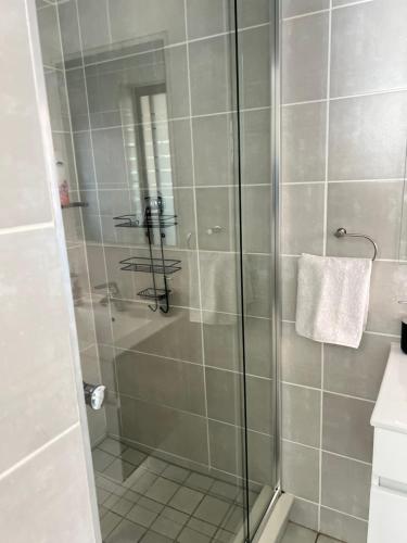 una ducha con puerta de cristal en un baño en Olive Luxe at The Blyde, en Pretoria