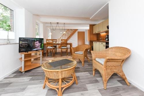 a kitchen and dining room with wicker chairs and a television at Ferienwohnung auf dem Hof Tjarks in Friedrichsschleuse
